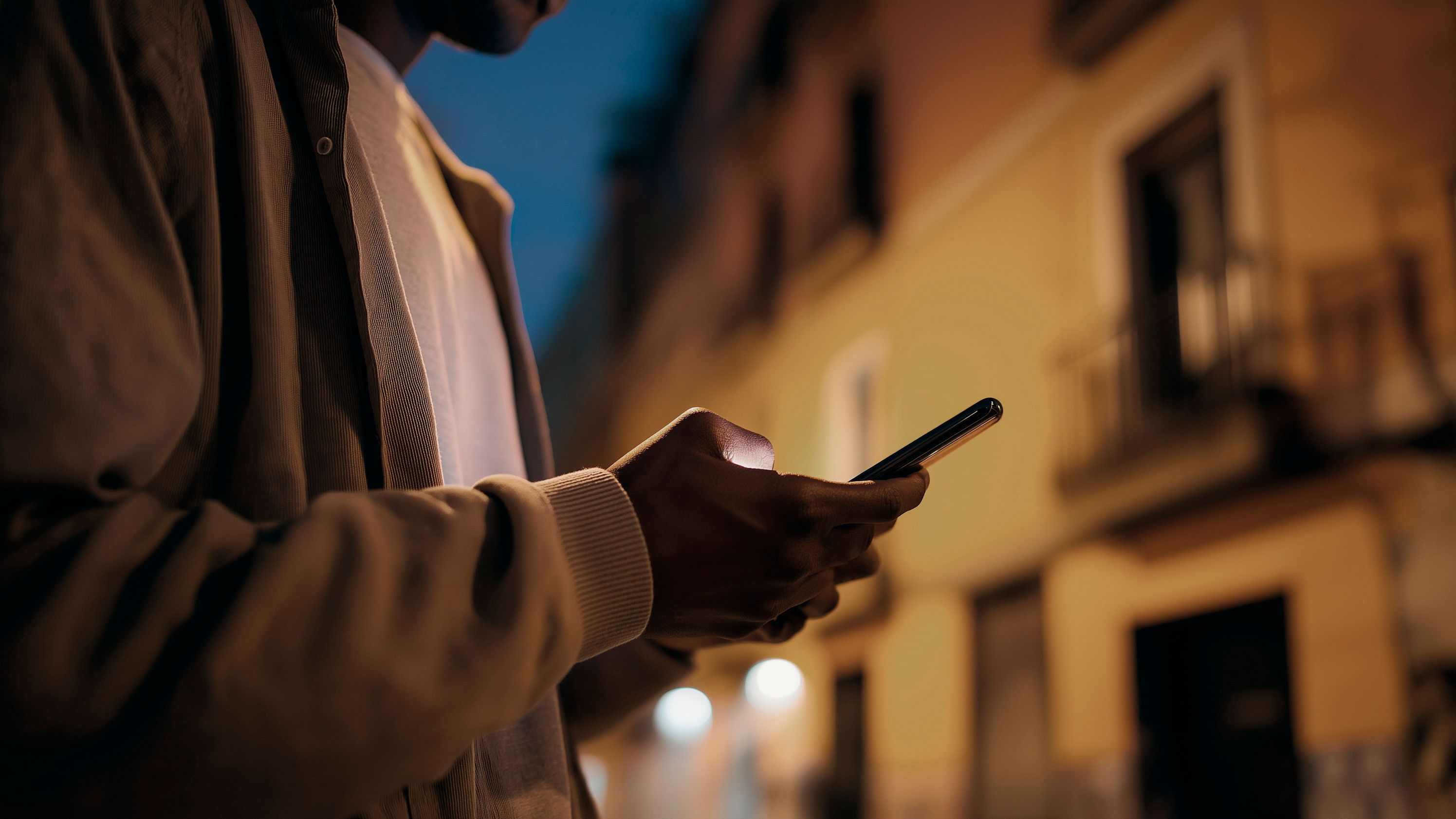 Detailansicht eines Mannes, der ein Smartphone in den Händen hält.