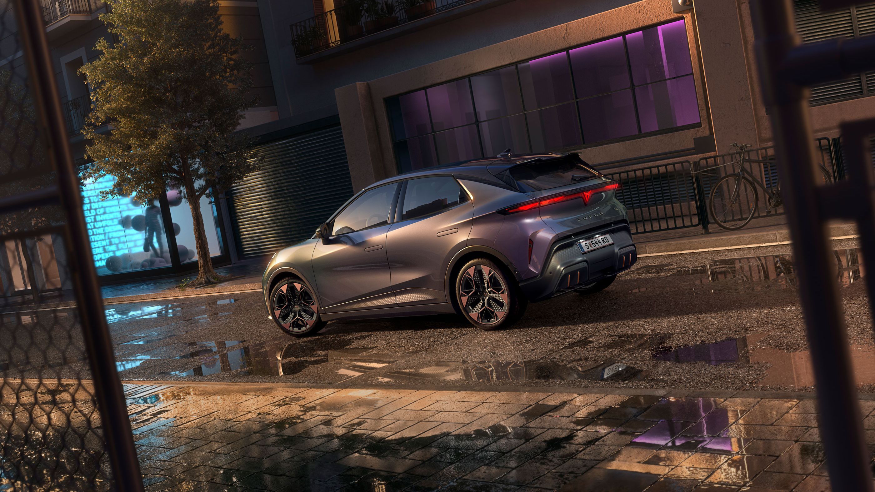 Nahaufnahme der Heckansicht des CUPRA Raval VZ in Plasma mit 19-Zoll-Felgen, geparkt auf einer städtischen Straße bei Nacht.