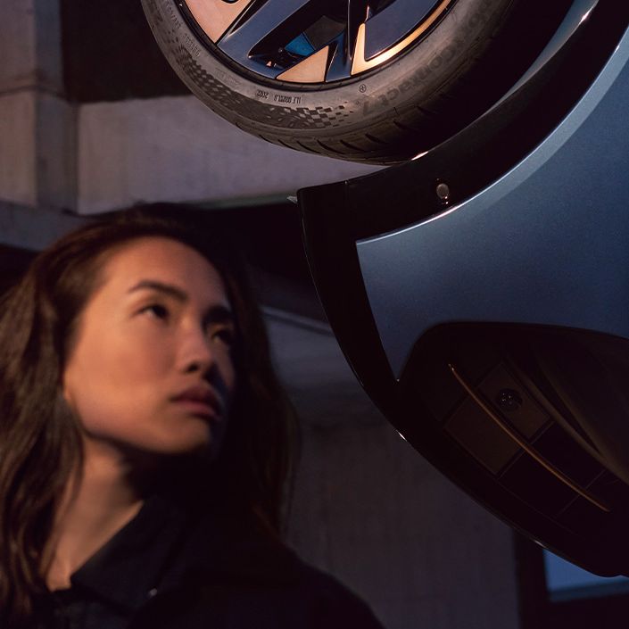 Detailansicht einer Felge des CUPRA Tavascan, eine Frau befindet sich neben dem Fahrzeug.