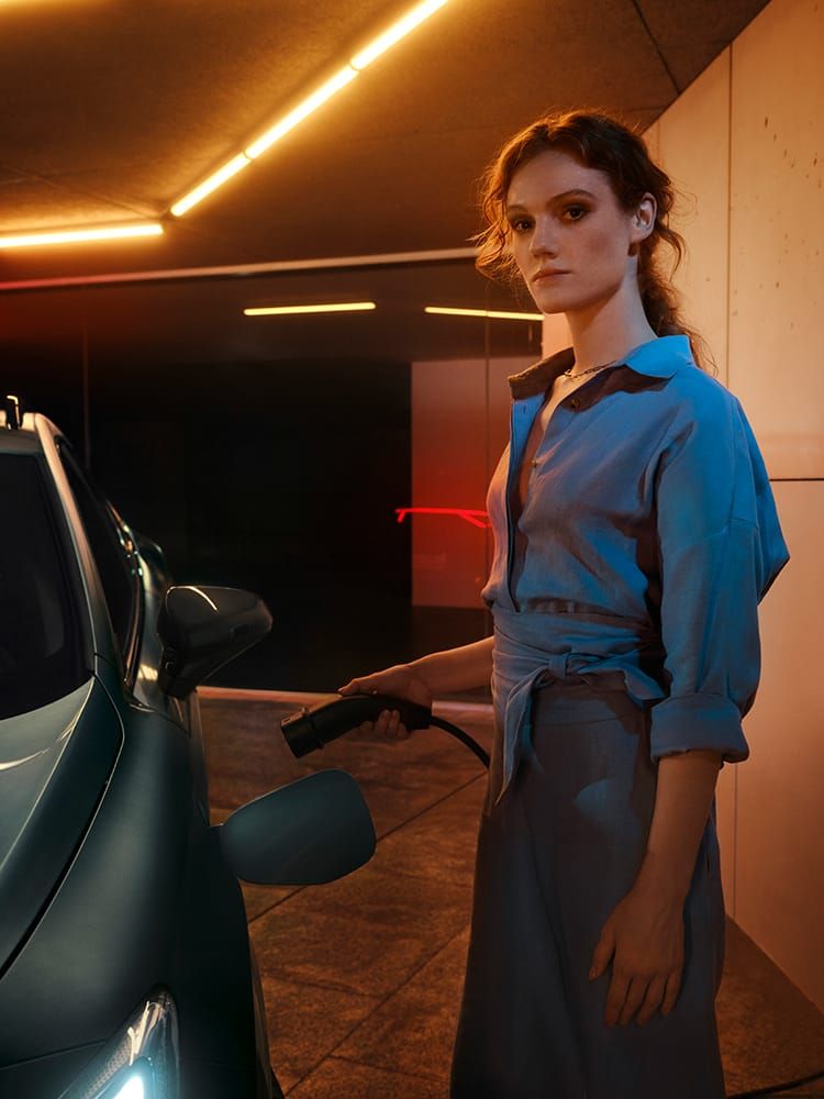 Eine Frau, die seitlich angelehnt neben einem CUPRA steht 